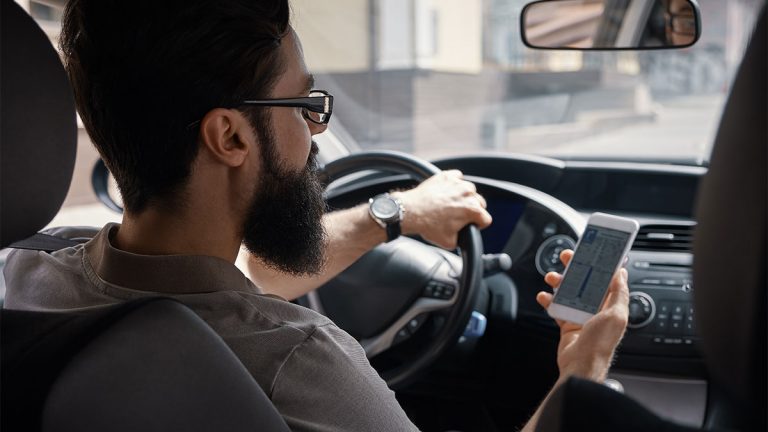 Motorista de aplicativo mexendo no celular dentro do carro