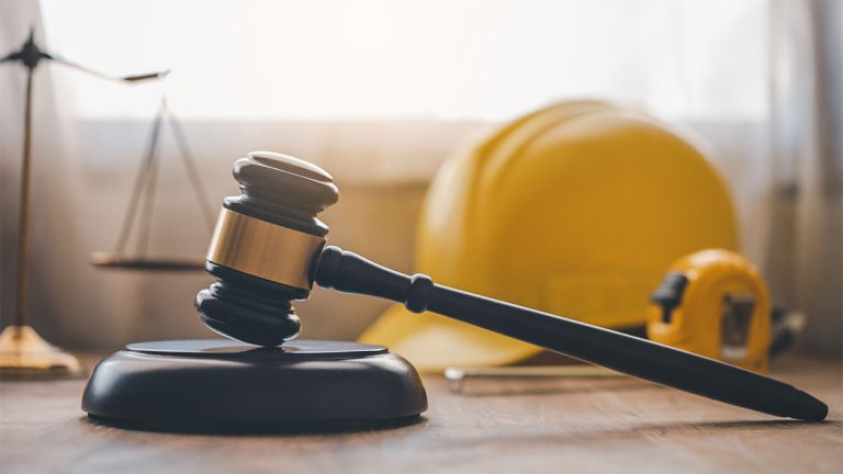 Martelo do juiz, balança da justiça e capacete de segurança representando o ajuizamento trabalhista e a relação entre justiça e trabalho.