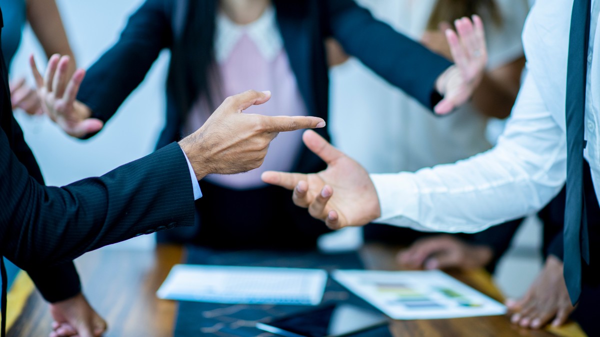 Profissionais em reunião corporativa discutindo estratégias de prevenção de conflitos trabalhistas, com gestos de diálogo e documentos sobre a mesa, demonstrando mediação e comunicação efetiva no ambiente organizacional