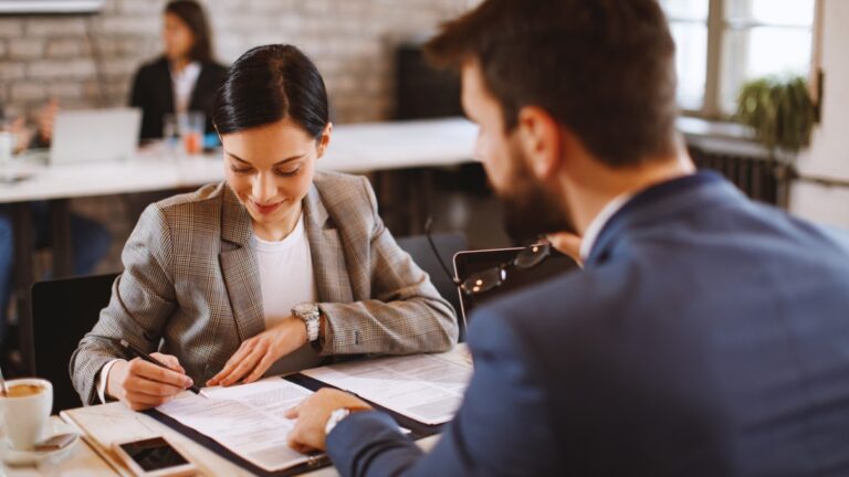 Profissional de RH realizando gestão de rescisões trabalhistas em reunião com colaborador, analisando documentos de verbas rescisórias, férias proporcionais e 13º salário em ambiente corporativo