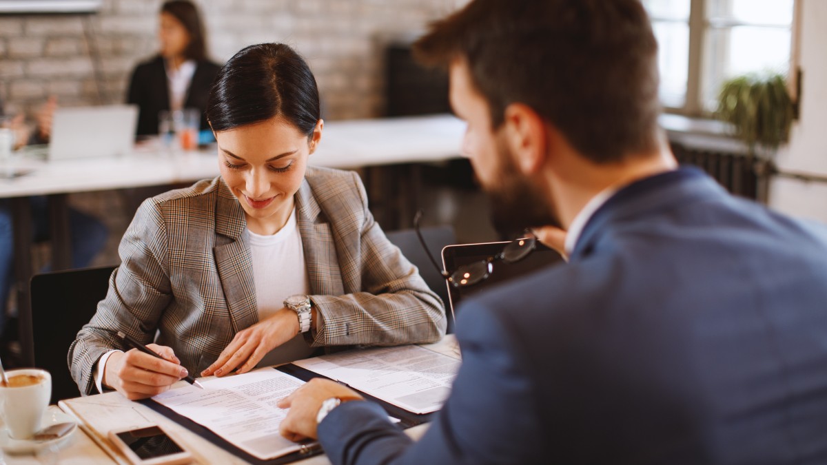 Profissional de RH realizando gestão de rescisões trabalhistas em reunião com colaborador, analisando documentos de verbas rescisórias, férias proporcionais e 13º salário em ambiente corporativo